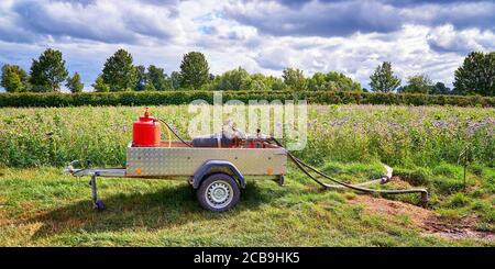 Wasserpumpe mit Motor auf einem Autoanhänger in einem Feld. Stockfoto