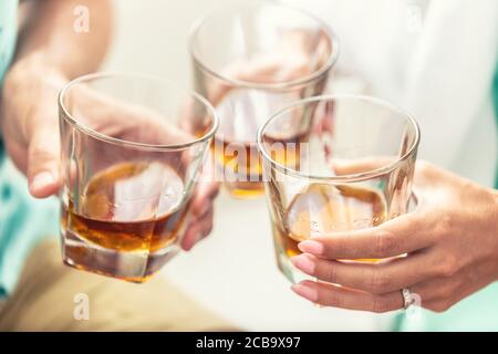 Gruppe von Freunden Toasten mit Gläsern von Whiskey Brandy oder Rum drinnen - Nahaufnahme Stockfoto