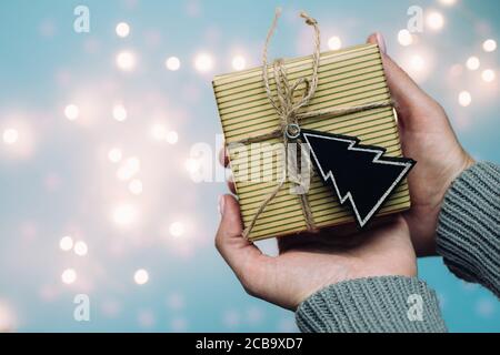 Die Hände der Frau halten weihnachten oder Neujahr dekorierte Geschenkbox. Getöntes Bild. Verschwommenes Licht im Hintergrund. Frohes Neues Jahr 2020 Stockfoto