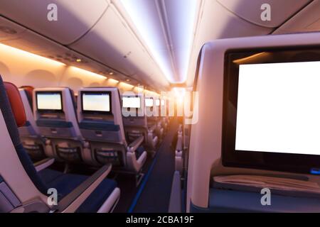 Flugzeuginnenraum mit Sitzreihen und leeren Touch-Entertainment-Bildschirmen. Konzept von schnellem Reisen und neuen Technologien. Stockfoto