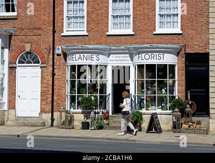 Frau, die an Floristin auf der Bridge Street, Tadcaster, North Yorkshire, England vorbeigeht Stockfoto