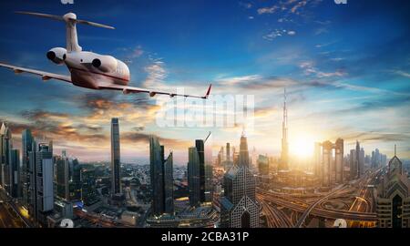 Private Jet Ebene über Dubai Stadt im schönen Abendlicht fliegen. Moderne und schnellste Verkehrsmittel, Business leben. Stockfoto