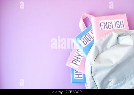 Flache Lage Zusammensetzung mit Rucksack und Schulbedarf und Themenbücher auf farbigem Hintergrund. Kopierraum Stockfoto