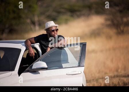 Erfolgreicher afrikanischer oder afroamerikanischer Schwarzmann auf Safari mit Luxuswagen Stockfoto