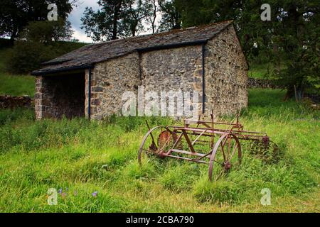 Alte Landmaschinen vor einer alten Scheune in Malham, Yorkshire Dales Stockfoto