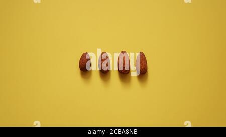 Die vier Mandeln in Reihe auf gelbem Hintergrund Stockfoto