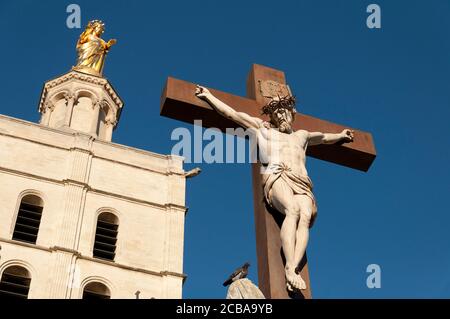 Im Vordergrund die Statue von Jesus Christus am Kreuz, im Hintergrund die Kathedrale von Avignon (Kathedrale Notre Dame des Doms), ist eine römisch-katholische Ca Stockfoto