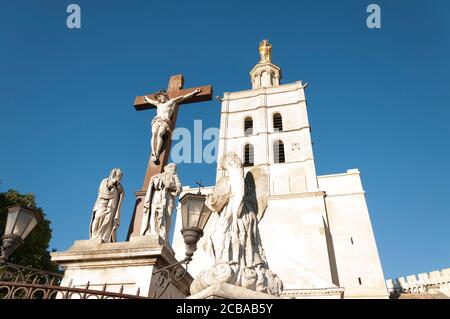 Im Vordergrund die Statue von Jesus Christus am Kreuz, im Hintergrund die Kathedrale von Avignon (Kathedrale Notre Dame des Doms), ist eine römisch-katholische Ca Stockfoto