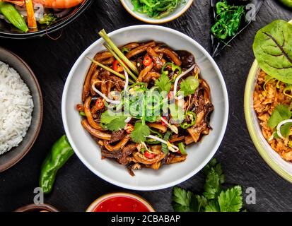 Asiatische udon Nudeln mit würziger Sojasauce und Hühnerteile, Ansicht von oben, auf schwarzen Stein serviert. Stockfoto