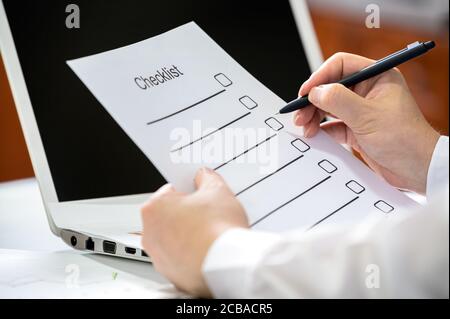 Hand eines Geschäftsmannes, der einen Stift hält und die Checkliste überprüft. Stockfoto