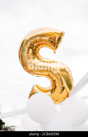 S-förmigen Helium Gold Ballon, auf einem weißen Hintergrund Himmel. Stockfoto