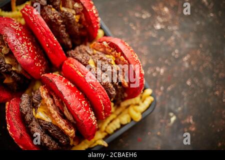 Set aus vier hausgemachten riesigen Doppel becon Käse Burger. Serviert mit pommes frites auf Holzbrett. Stockfoto