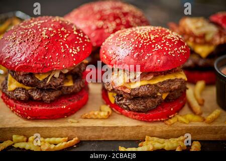 Set aus vier hausgemachten riesigen Doppel becon Käse Burger. Serviert mit pommes frites auf Holzbrett. Stockfoto