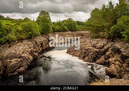 Das Wasser des Ken Flusses fließt durch eine felsige Schlucht in Galloway, Schottland, aufgrund des Earlstoun Dam und des Loch / Stausees, auf dem Galloway Hydro Stockfoto