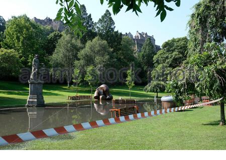 Edinburgh, Schottland, Großbritannien. August 2020. Sonniges Wetter ersetzt nächtliche Gewitter, die die West Princes Street Gardens überschwemmt und der Öffentlichkeit abgesperrt lassen. Elephant Bronze Skulptur gefangen in den Fluten. Blick auf das Edinburgh Castle. Kredit: Craig Brown/Alamy Live Nachrichten Stockfoto