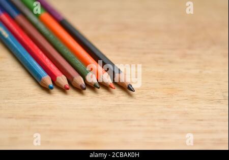 Abstract Flat Lay / Layout mit geschärften Farbstiften auf einem Holzbrett platziert. Blau, Rot, Orange, Grün, Schwarz Farben sind hier zu sehen Stockfoto