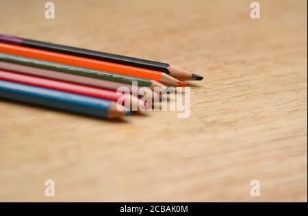 Abstract Flat Lay / Layout mit geschärften Farbstiften auf einem Holzbrett platziert. Blau, Rot, Orange, Grün, Schwarz Farben sind hier zu sehen Stockfoto