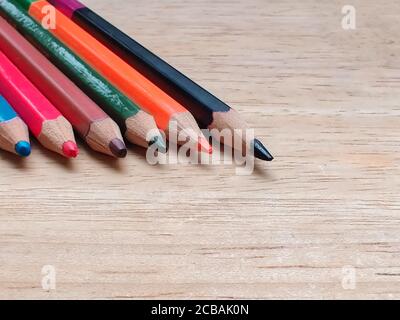 Abstract Flat Lay / Layout mit geschärften Farbstiften auf einem Holzbrett platziert. Blau, Rot, Orange, Grün, Schwarz Farben sind hier zu sehen Stockfoto