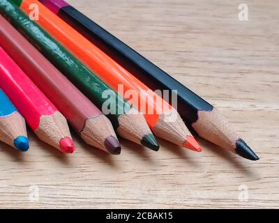 Abstract Flat Lay / Layout mit geschärften Farbstiften auf einem Holzbrett platziert. Blau, Rot, Orange, Grün, Schwarz Farben sind hier zu sehen Stockfoto