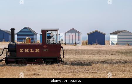 Eine Lokomotive der Hayling Seaside Railway fährt an Strandhütten vorbei, während sie Passagiere entlang der Eisenbahn auf Hayling Island, Hampshire, befördert. Stockfoto