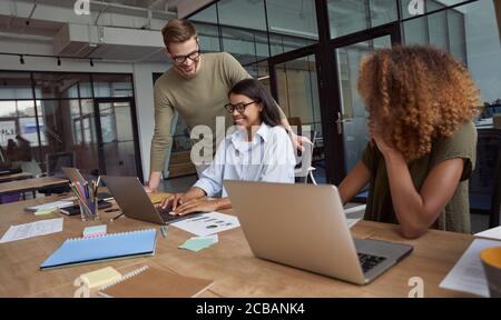 Gruppe von glücklichen Kollegen, multirassische Business-Team arbeiten sitzen im modernen Coworking Space und arbeiten zusammen, etwas zu diskutieren und Stockfoto