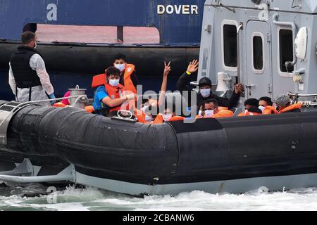 Eine Gruppe von Menschen, die als Migranten gedacht werden, eine winkt, werden von Grenzbeamten nach einer Reihe von kleinen Bootsvorfällen im Kanal heute in Dover, Kent, gebracht. Stockfoto