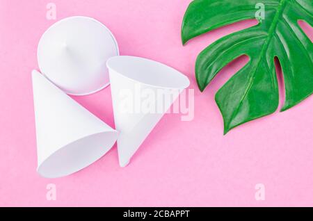 Einweg-Papier Konus Wasserbecher mit grünem Blatt auf rosa Hintergrund. Stockfoto