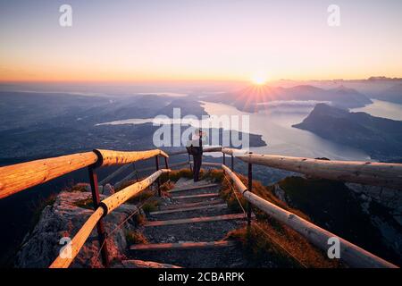 Mann fotografiert Landschaft mit See und Bergen bei schönem Sonnenaufgang. Blick vom Pilatus-Berg, Luzern, Schweiz Stockfoto
