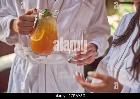 Man Hand Gießen orange Limonade in Glas Stockfoto