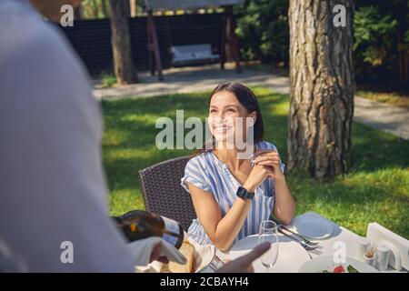 Der Kellner zeigte der schönen Frau eine Flasche Weißwein Stockfoto