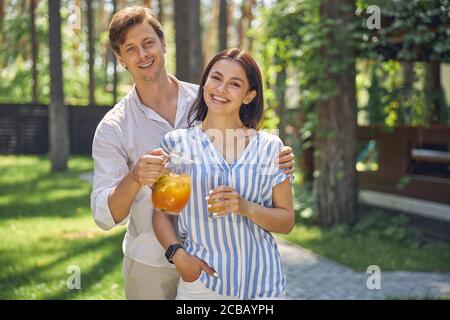 Schönes lächelndes Paar mit oranger Limonade, die im Freien steht Stockfoto