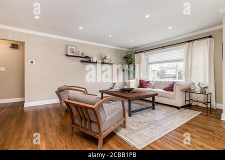 ELMHURST, IL, USA - 15. MÄRZ 2020: Ein großes Wohnzimmer mit Stühlen, Couch und Holzcouchtisch. Stockfoto