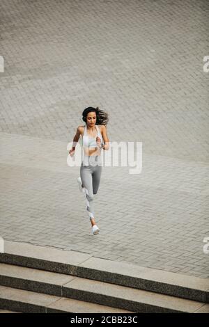 Blickfeld einer sportlichen Frau, die im Freien läuft. Hündin in Sportswear sprintet morgens.