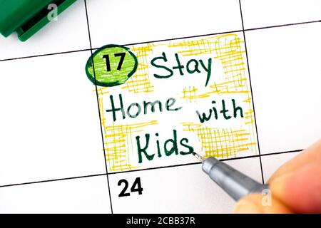 Frau Finger mit Stift Schreiben Erinnerung Aufenthalt zu Hause mit Kindern im Kalender. August 17. Stockfoto