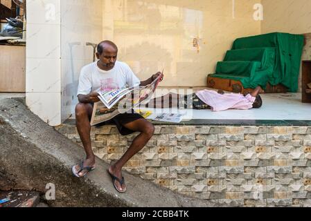 Mumbai, Indien - 22. November 2019: Nicht identifizierter Mann liest Zeitung auf der Straße in Mumbai (umgangssprachlich bekannt als Bombay), Indien. Stockfoto