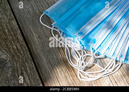 Coronavirus-Schutz. Blaue antivirale medizinische Gesichtsmasken. Chirurgische Schutzmasken mit Ohrschlaufen auf einem Holztisch. Stockfoto