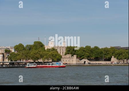 Touristen genießen eine Kreuzfahrt auf der Themse mit dem herrlichen Tower of London im Hintergrund. Stockfoto