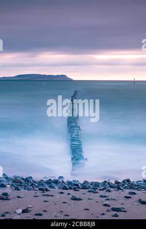 Langzeitbelichtung des Sonnenaufgangs über der Ostsee und LON-Linien von hölzernen Wellenbrecher auf den coas. Stockfoto