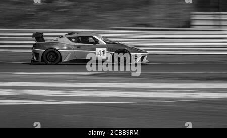 Eine monochrome Schwenkaufnahme eines Rennwagens, der eine Strecke fährt. Stockfoto