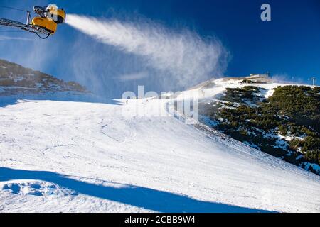 Schneekanon bedeckt die Piste im Skigebiet mit frischem Pulverschnee. Das Spritzen von Wasser im Winter schaffen Wolke von Schneeflocken. Stockfoto