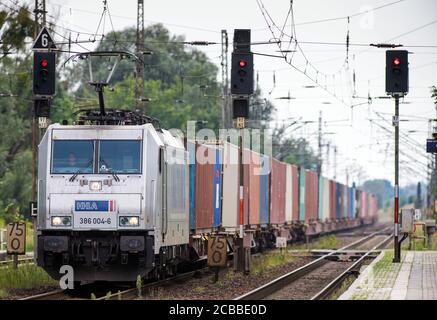 Wustermark, Deutschland. August 2020. Ein Güterzug, der von einer elektrischen Lokomotive der Hamburger Hafen und Logistik AG (HHLA) gezogen wird, passiert den Bahnhof im Dorf Priort. Quelle: Soeren Stache/dpa-Zentralbild/ZB/dpa/Alamy Live News Stockfoto