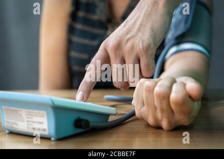 Nahaufnahme einer Hand, die auf ein Gerät zur Messung des arteriellen Drucks zeigt. Stockfoto