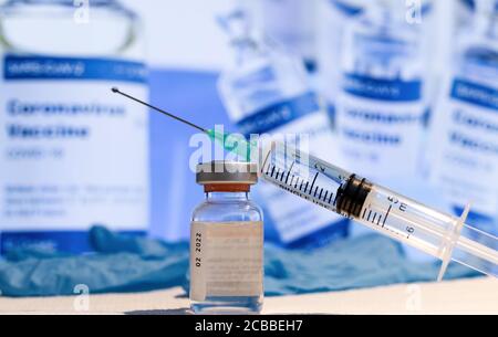 Ampulle mit Impfstoff und einer Spritze mit einer Nadel vor einer Medikamentenflasche. Medizin, Wissenschaft und Gesundheitskonzept. Stockfoto