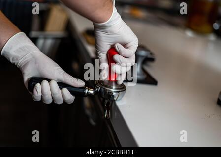 Barista macht Kaffee, hält einen porta-Filter in der Hand und presst Kaffee. Stockfoto