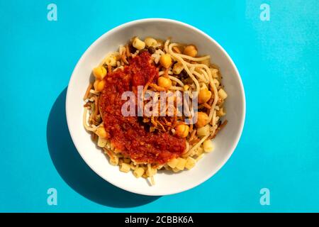 Berühmte traditionelle arabische, ägyptische Gericht - Koshari. National Kushari in einer weißen Platte auf blauem Hintergrund. Flach liegend, Draufsicht. Stockfoto