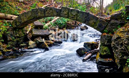 Die Landschaft im Herbst mit einer Steinbrücke und Fluss rasant Stockfoto