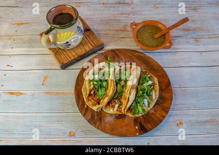 Mexikanische Tacos mit Barbacoa, grüner Sauce und Cafe de la olla Stockfoto