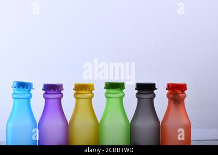 Set von Flaschen in verschiedenen Farben. Reihe von bunten alkoholfreien Getränken auf hellgrauem Hintergrund. Energy Drinks Behälter mit verschiedenen Geschmacksrichtungen auf Holztisch. Farbauswahl und Behälterkonzept. Stockfoto