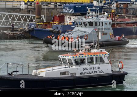 Migranten, die von der Grenztruppe an Land in den Hafen gebracht werden, während die Patrouille am Hafen von Dover beobachtet.immer mehr Migranten segeln in kleinen Booten aus französischen Hoheitsgewässern in den Ärmelkanal, wo sie von der britischen Grenztruppe legal an Land gebracht werden. Die Migranten können dann im Vereinigten Königreich Asyl beantragen. Stockfoto