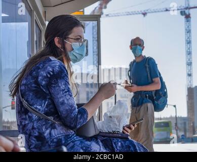 Jerusalem, Israel - 6. August 2020: Passagiere, die in COVID-Masken auf ihren Bus warten, in einem Busbahnhof in Jerusalem, Israel Stockfoto